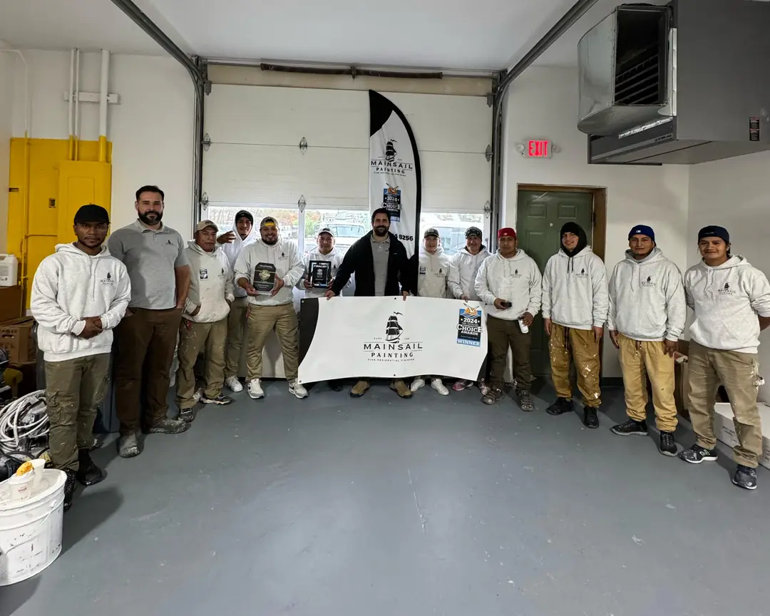 Equipe da Mainsail no galpão, com o banner, a bandeira e os troféus