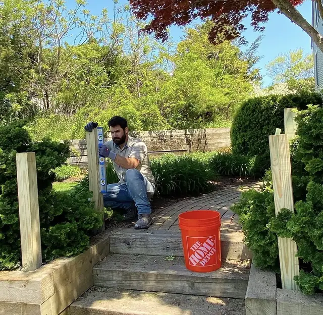 Vini nivelando postes de madeira num jardim