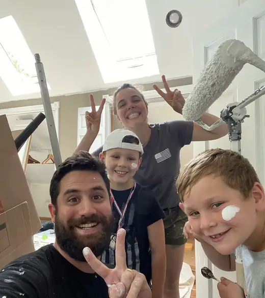 Vini, a esposa e as crianças com tinta no rosto numa sala em pintura